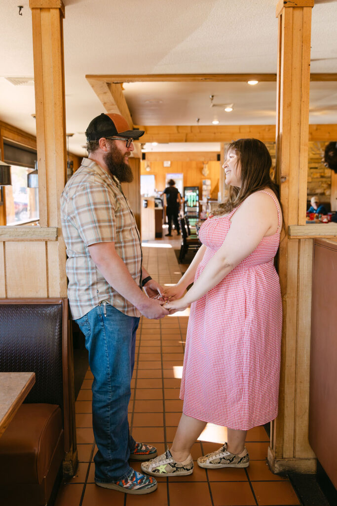 Couple holding hands and smiling inside Vern’s Place during their storytelling-style engagement session.