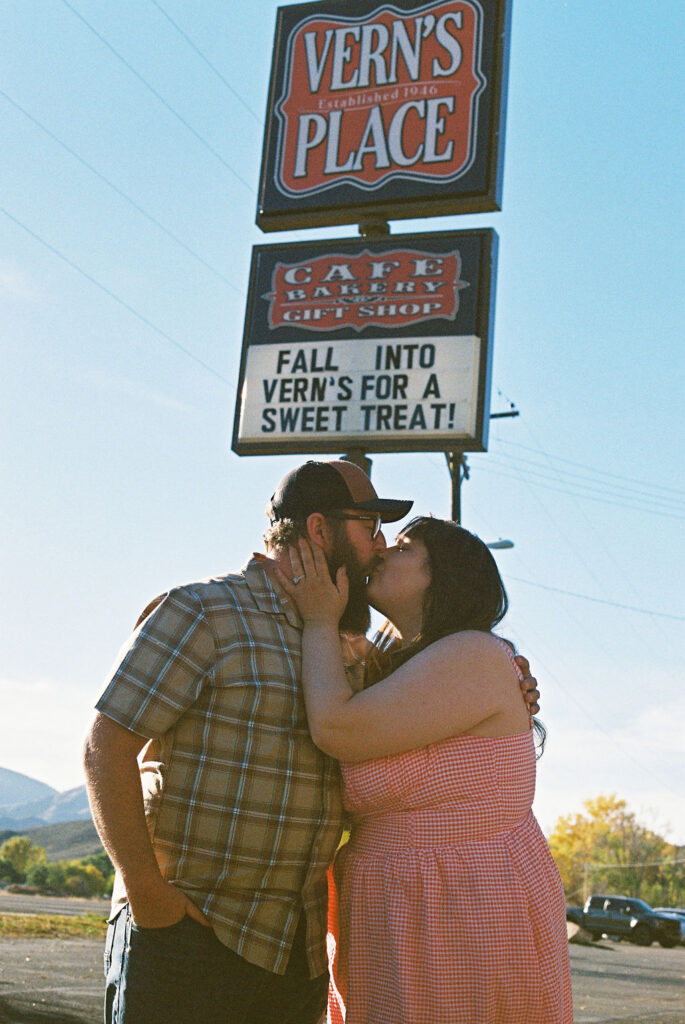 Couple kissing under the Vern’s Place sign during their nostalgic Colorado engagement session.
