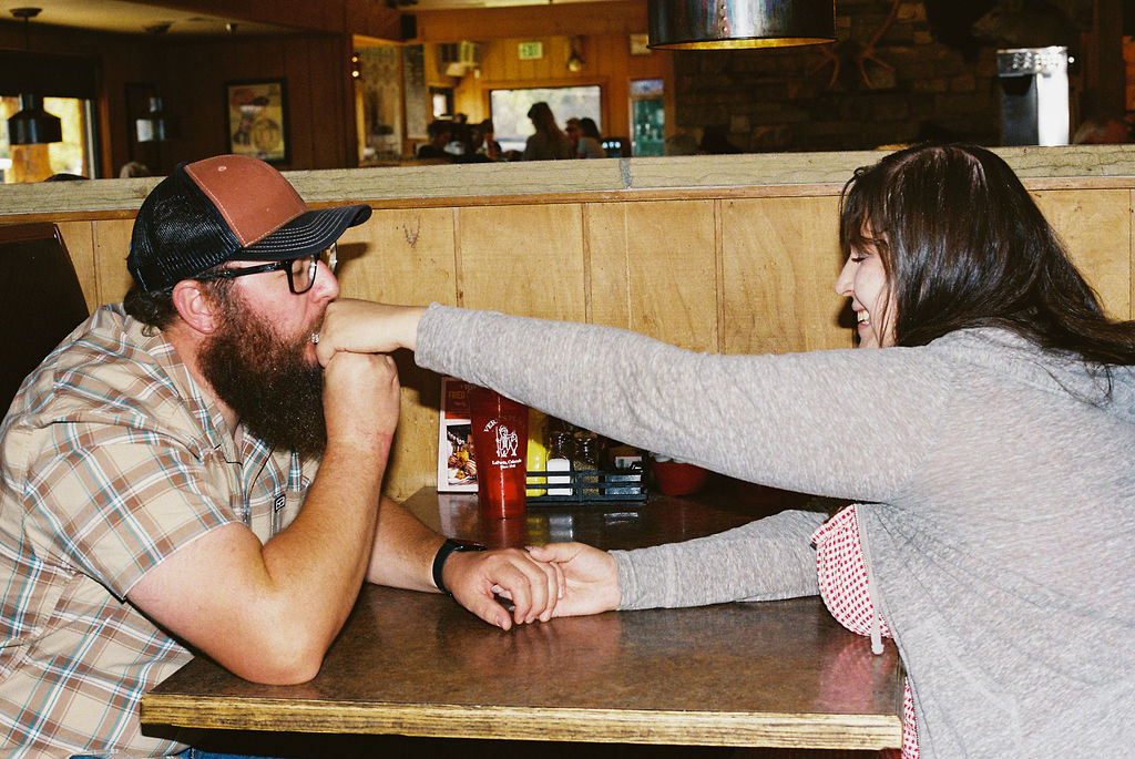 Couple sharing a romantic kiss on the hand across the diner booth at Vern's Place 