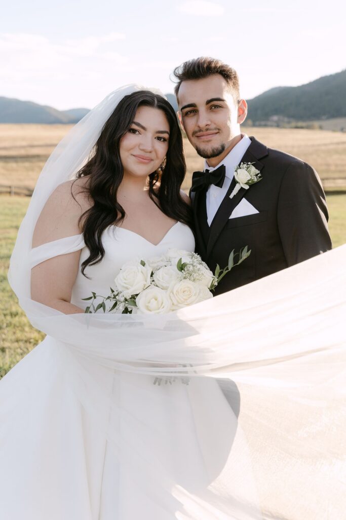 Classic wedding portrait of bride and groom under a cathedral length veil at sunset at Spruce Mountain Ranch wedding venue in Colorado 