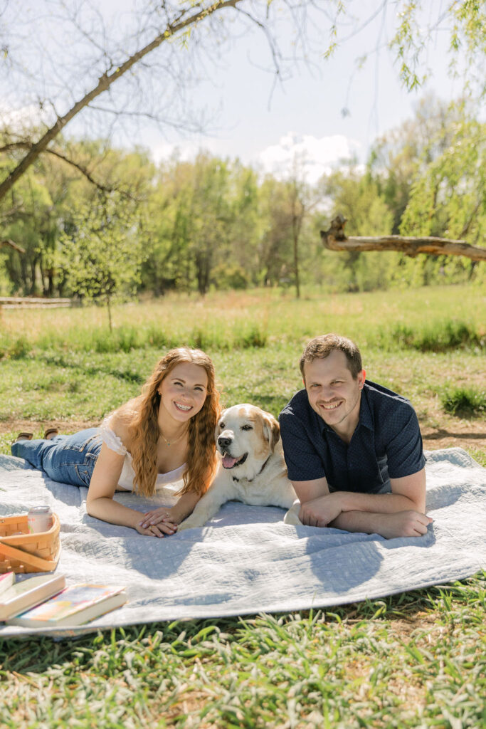 Annelise, Ross, and their dog laying on a picnic blanket during their Fort Collins engagement session.