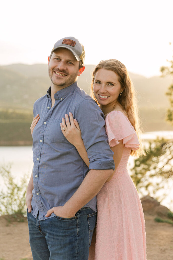 Close-up of couple smiling at the camera during their engagement session with Horsetooth reservoir and foothills behind them