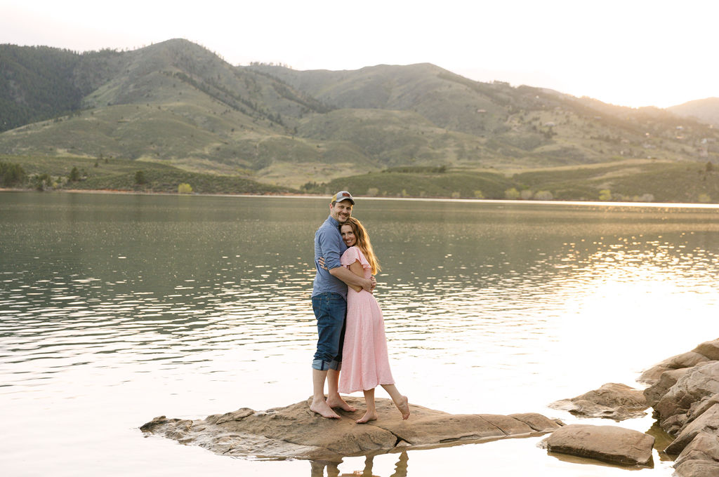 Couple embracing standing on rock at their Horsetooth reservoir engagement session in fort collins