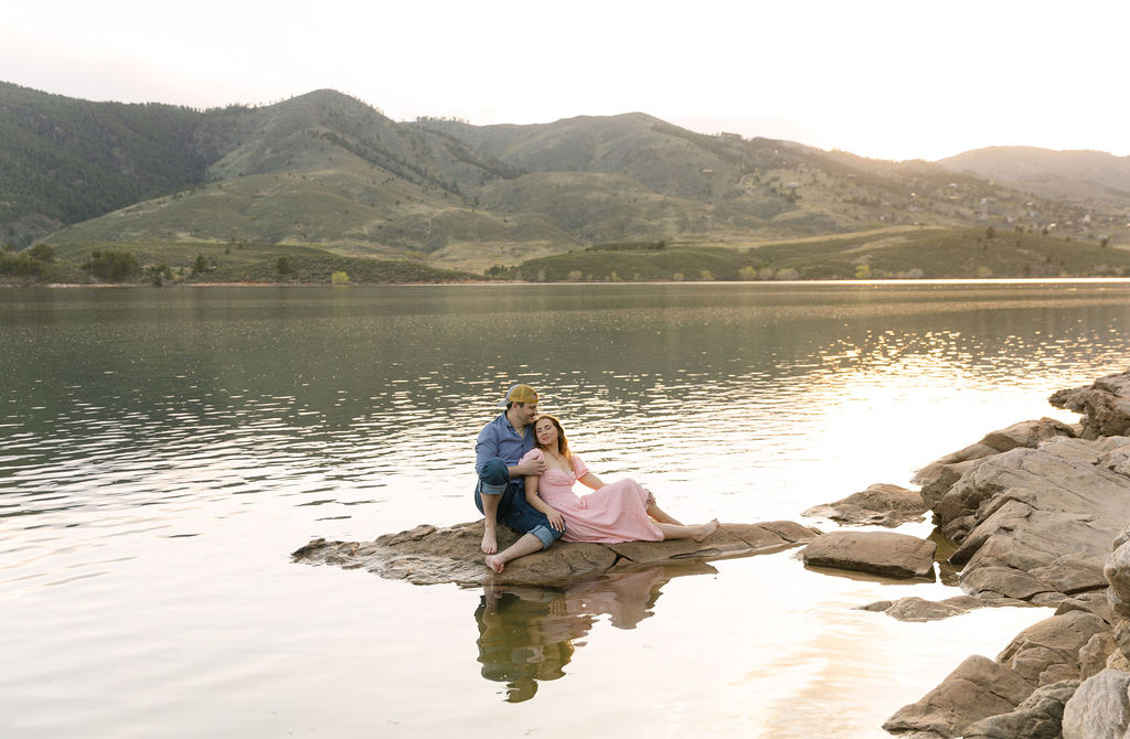 Couple sitting on the rocks by the water at Horsetooth Reservoir.