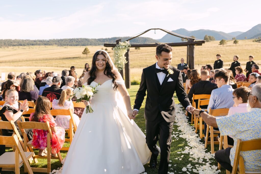Bride and groom walking out of their ceremony surrounded by guests at Spruce Mountain Ranch.