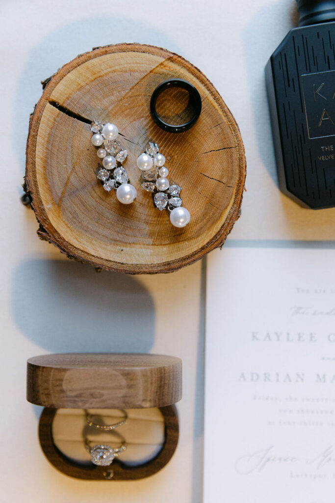 Detail photo of bridal accessories and rings styled on wood slices for a luxury Colorado wedding.