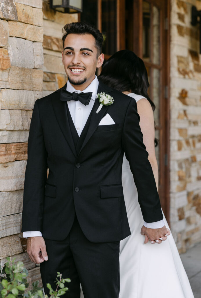 Groom smiling holding his bride's hand during their first touch outdoors at the best colorado mountain wedding venue 
