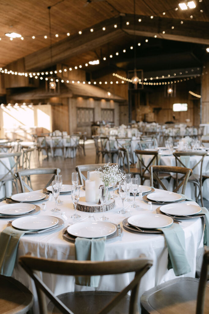 Luxury reception table settings at Spruce Mountain Ranch with white linens, gold flatware, and soft greenery.