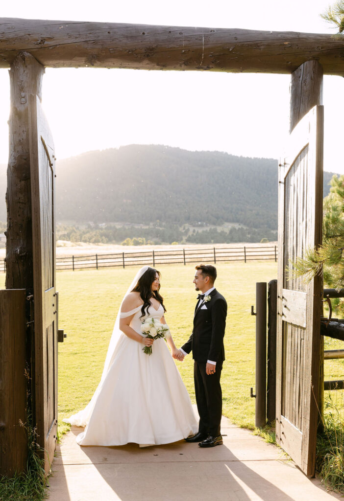 Bride and groom framed in barn doorway overlooking the mountains at Spruce Mountain Ranch.