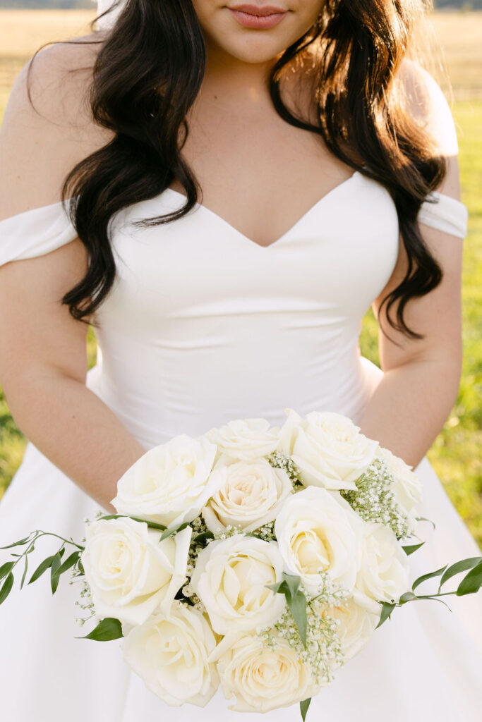 Close-up of bride’s bouquet with white roses and greenery.