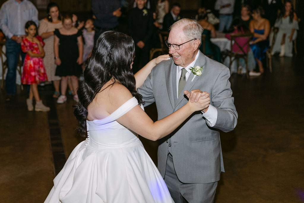 Bride laughing as she dances with her grandfather during the reception.