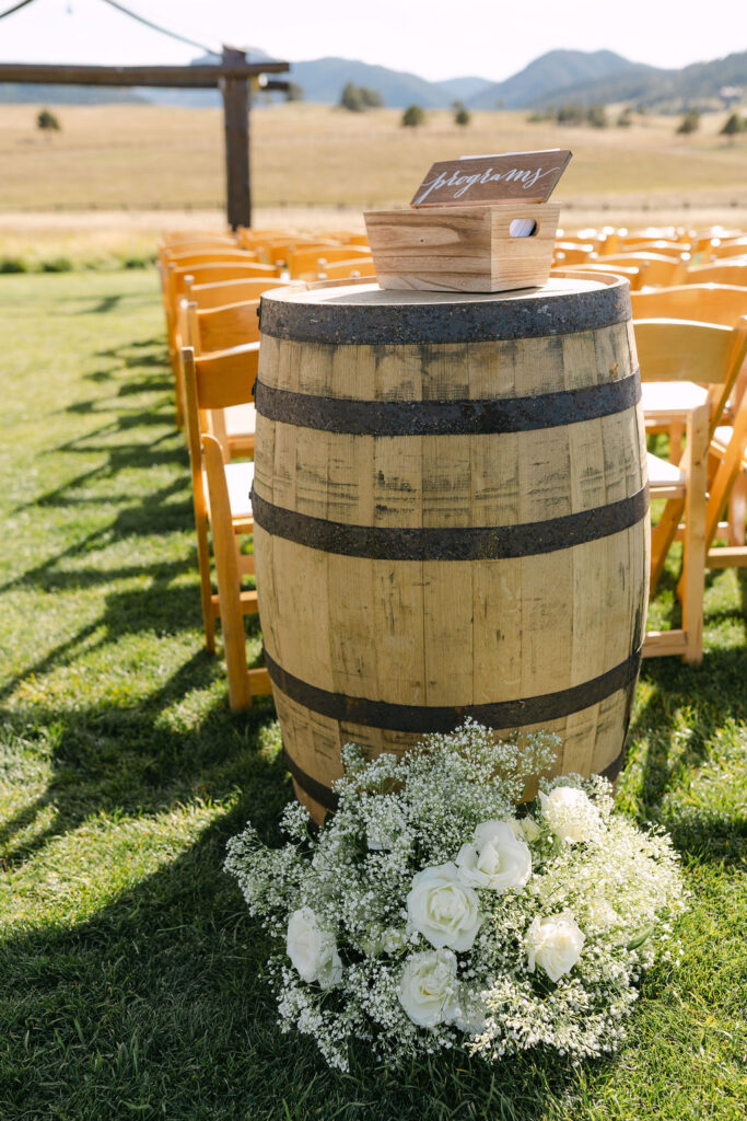 Wooden barrel with floral arrangements welcoming guests to a Spruce Mountain Ranch ceremony.