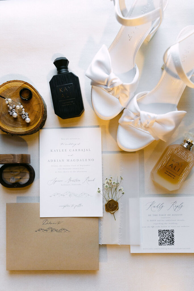 Flatlay of invitation suite and bridal details for a high-end Colorado ranch wedding.