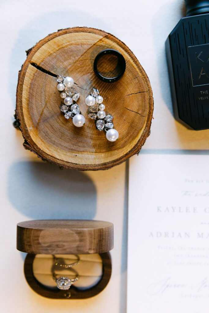 Detail photo of bridal accessories and rings styled on wood slices for a luxury Colorado wedding.