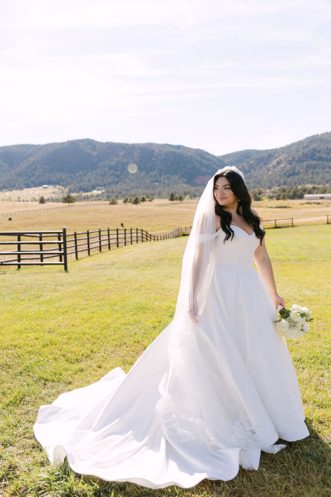 Bride smiling while standing in the open field at Spruce Mountain Ranch.
