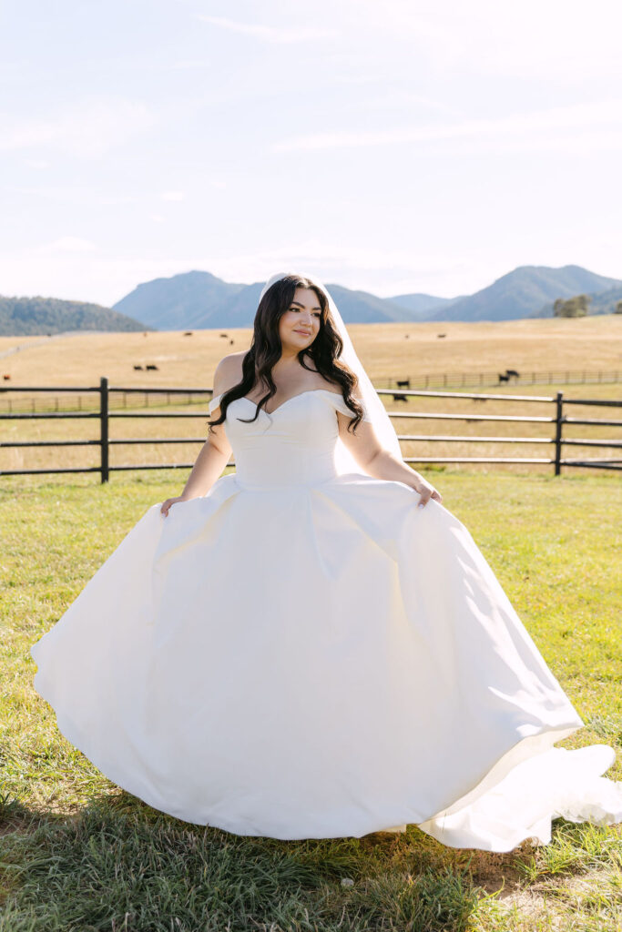 Bride walking through the open field with sweeping mountains behind her.