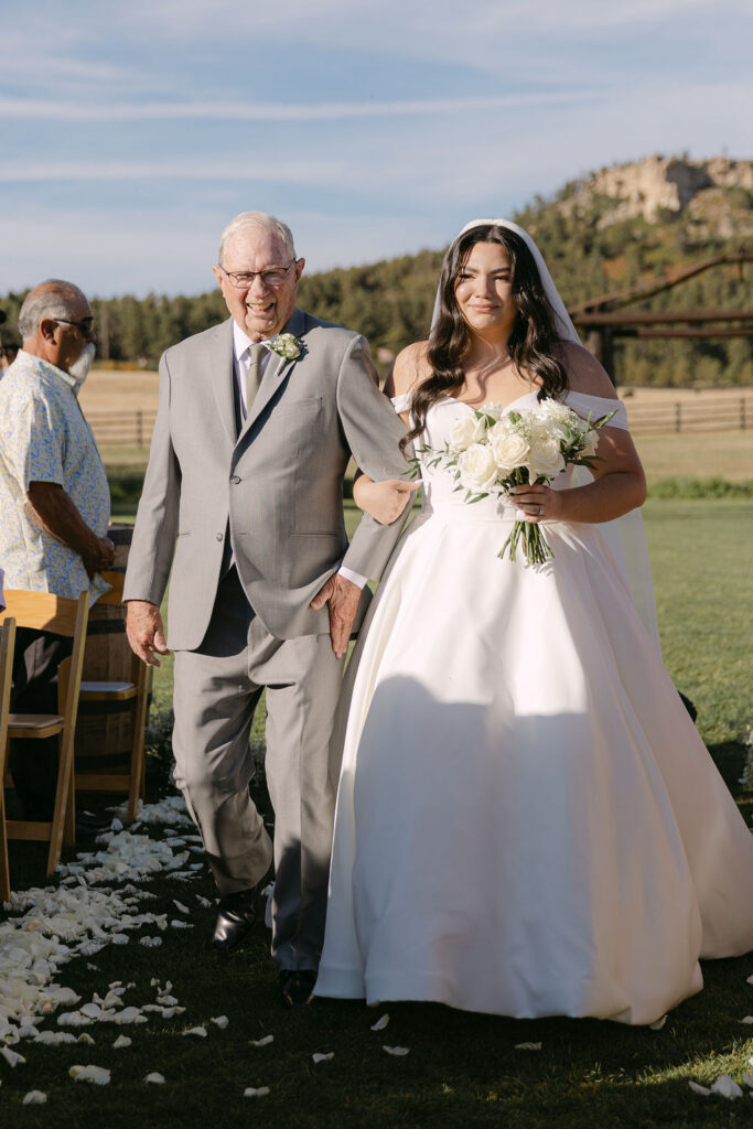 Bride walking down the aisle with grandfather at Spruce Mountain Ranch.