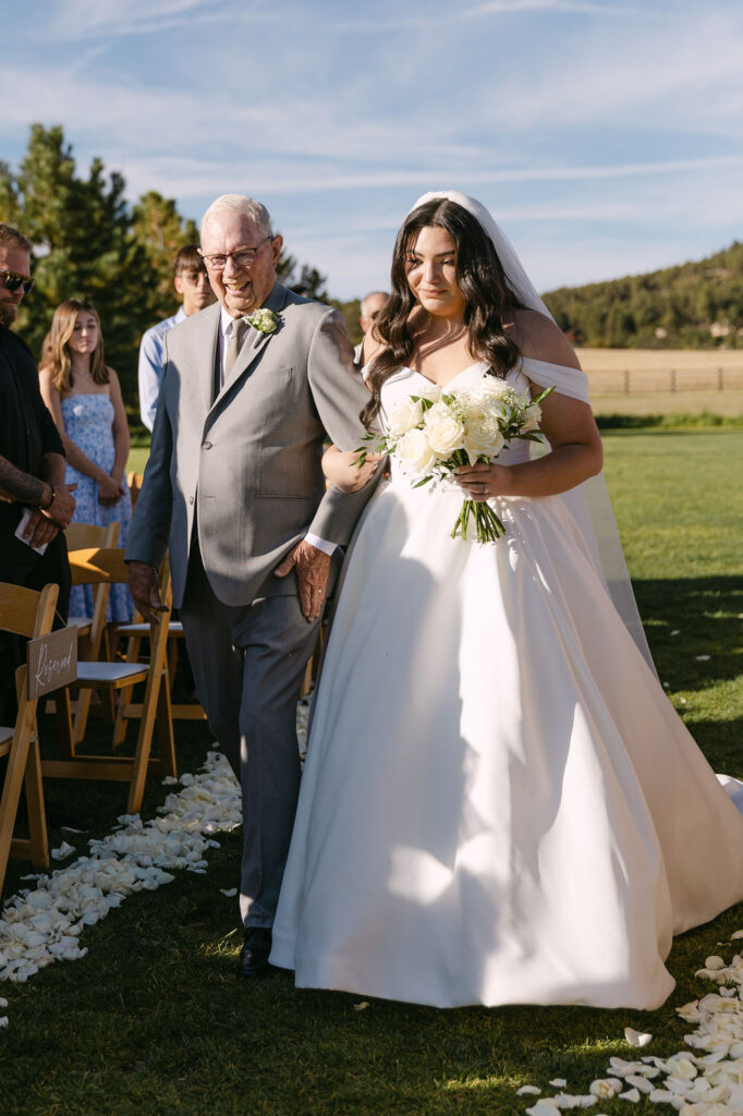 Bride walking down the aisle with grandfather at Spruce Mountain Ranch.