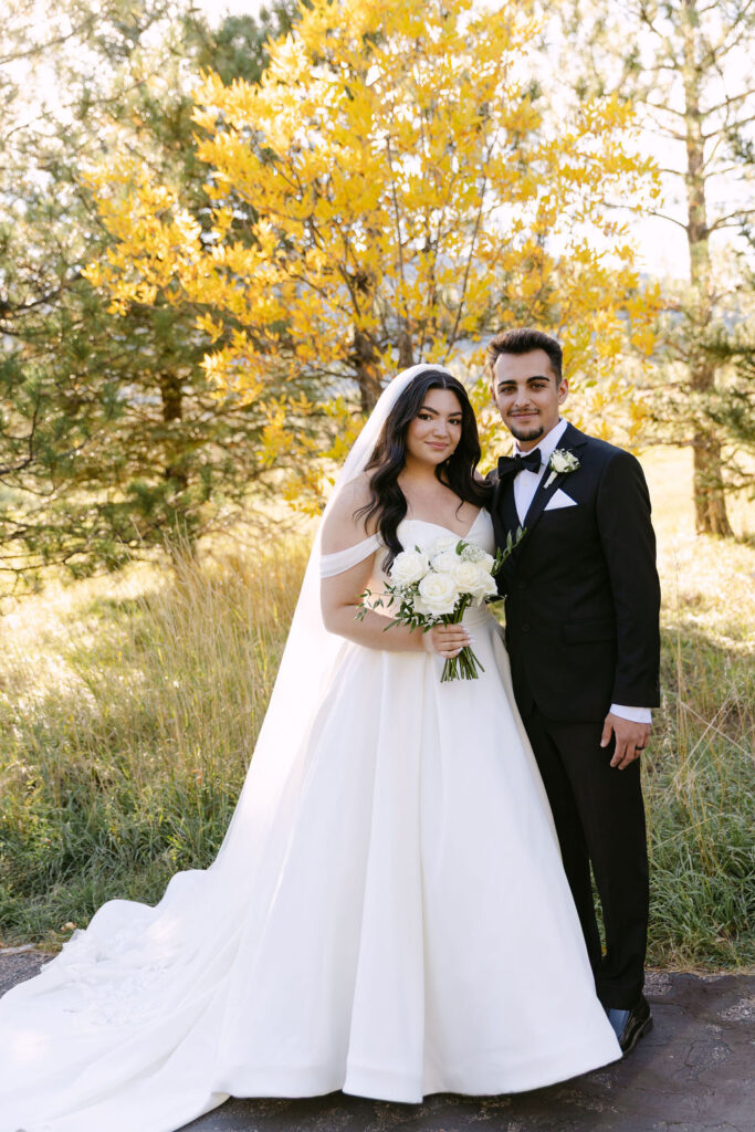 Bride and groom standing together surrounded by golden aspen trees at Spruce Mountain Ranch.