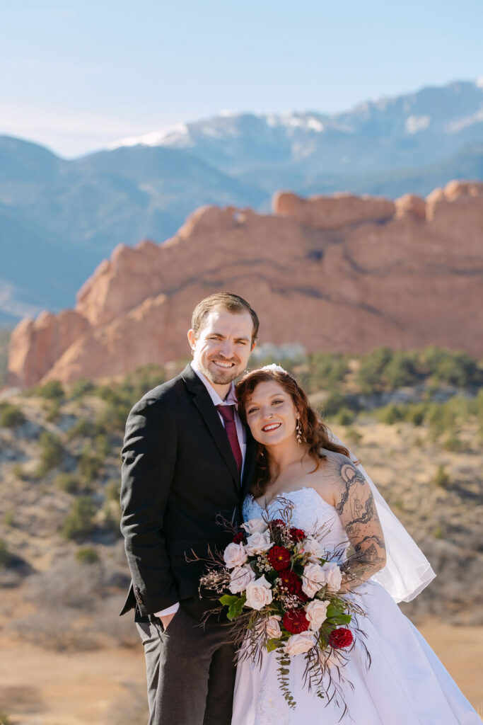 Classic wedding portrait of bride and groom smiling at the camera in the mountains 