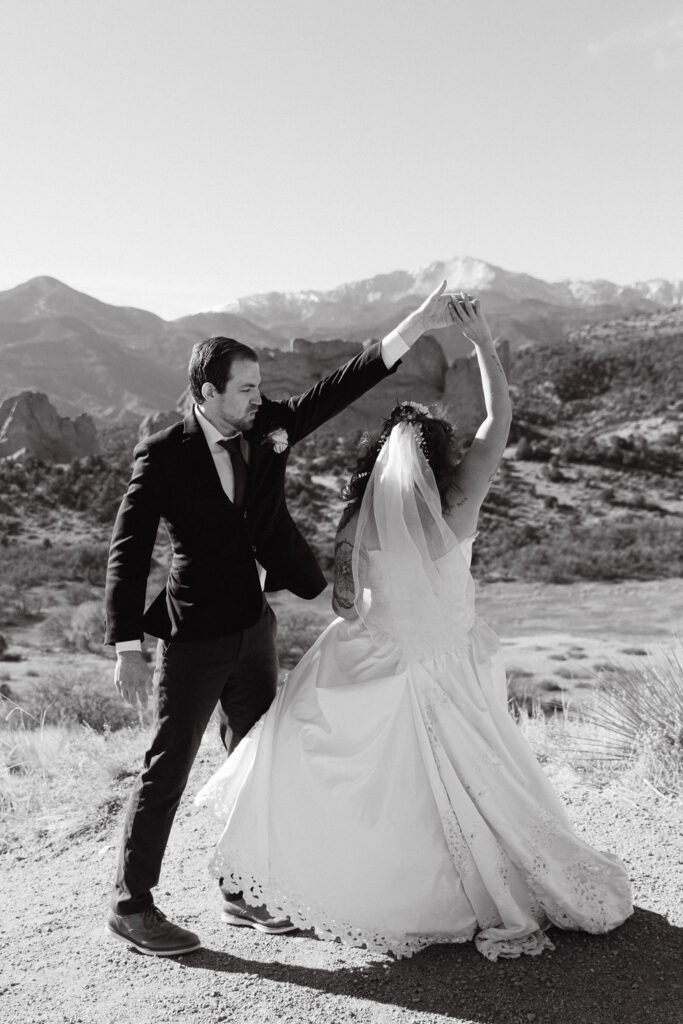 Black and white image of bride and groom dancing in Garden of the gods for their wedding photos 