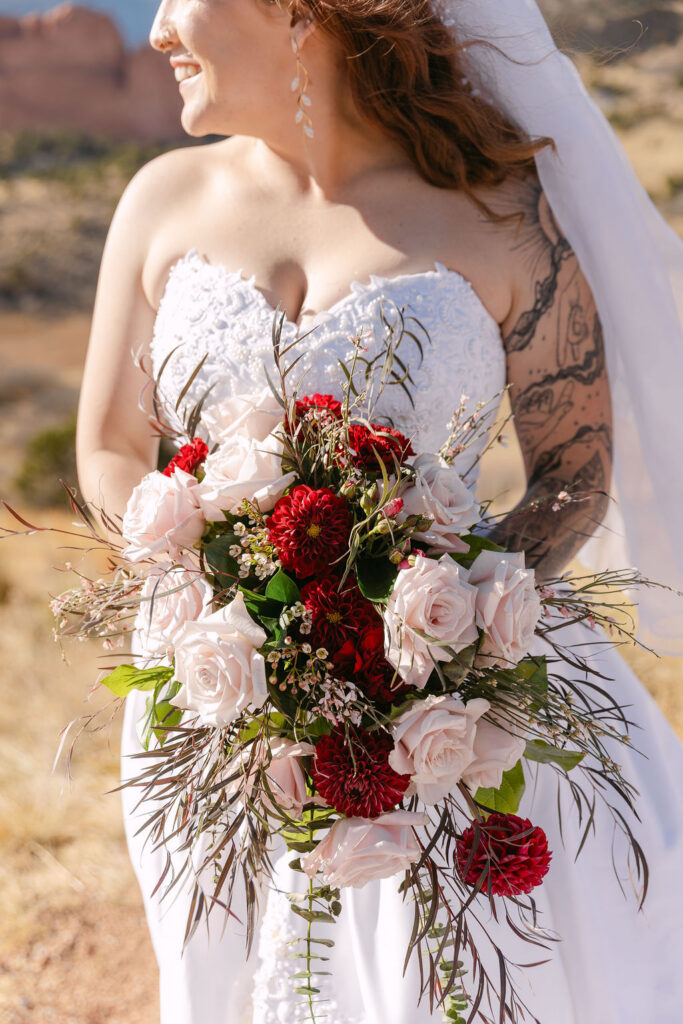 Bride holding her pink and red bridal bouquet in the sunlight during her Colorado mountain elopement
