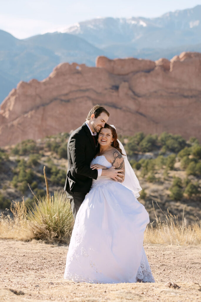 Classic wedding photo of bride and groom hugging and laughing at Garden of the gods 