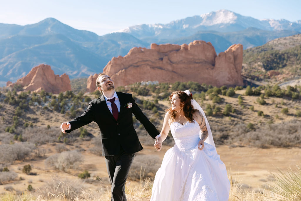 Candid wedding photography capturing a bride and groom laughing as they walk hand in hand during their garden of the gods wedding 