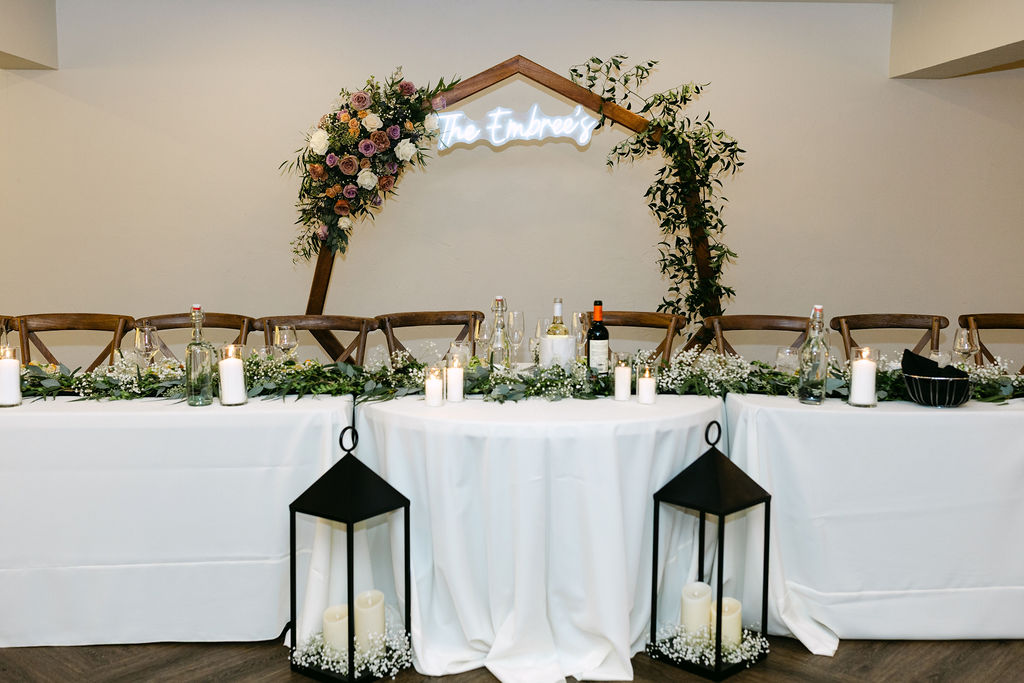 The reception head table with candles and florals is set inside Wild Basin Lodge in Allenspark, Colorado, near Rocky Mountain National Park.