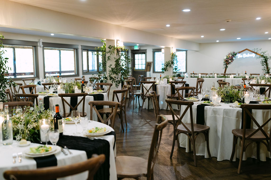 A wide view of the reception room set with tables and chairs inside Wild Basin Lodge in Allenspark, Colorado. 