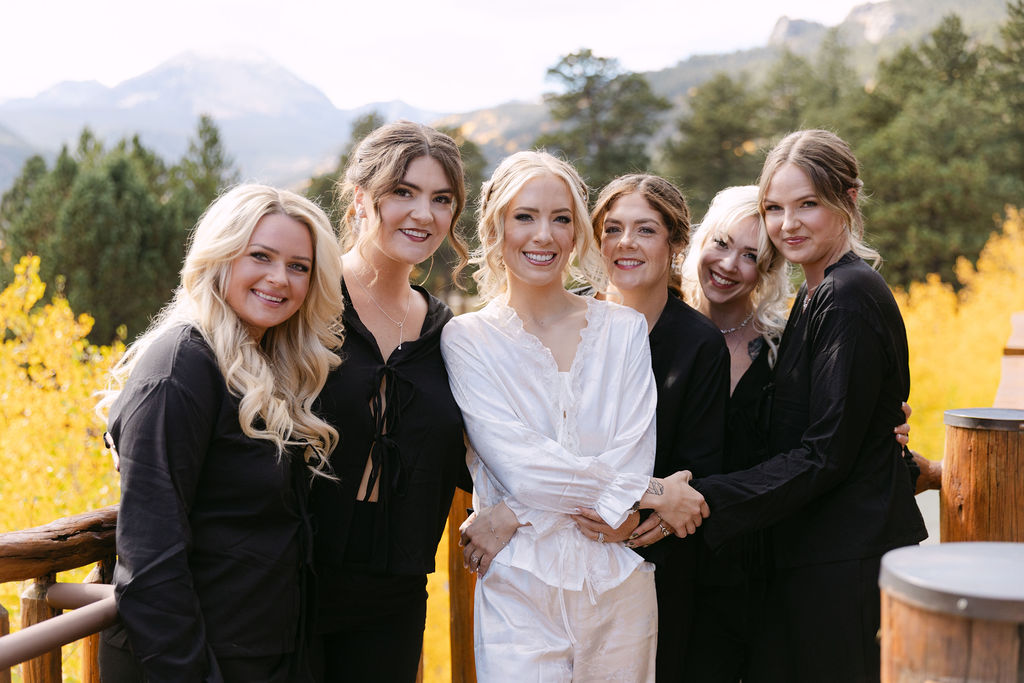 The bride stands with her wedding party outdoors at Wild Basin Lodge in Allenspark, Colorado, within Rocky Mountain National Park.