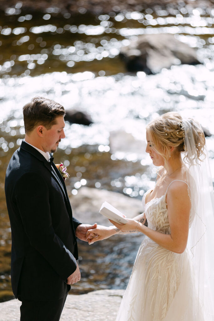 A close view of the couple holding hands while exchanging vows by the river during their wedding day. 