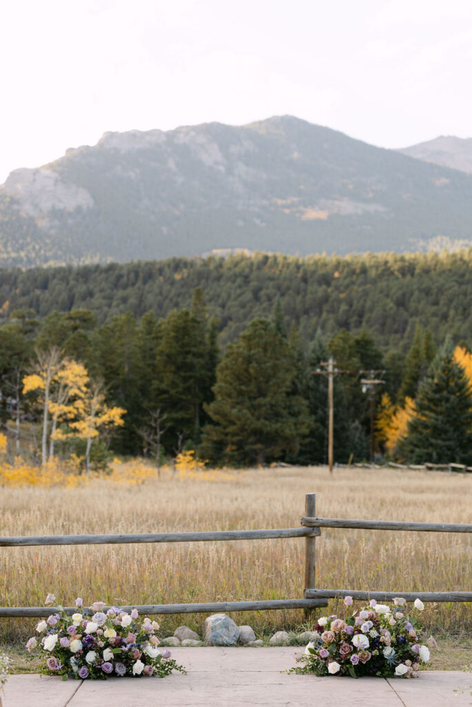 Ceremony florals are arranged along a stone aisle with mountain views at Wild Basin Lodge. 