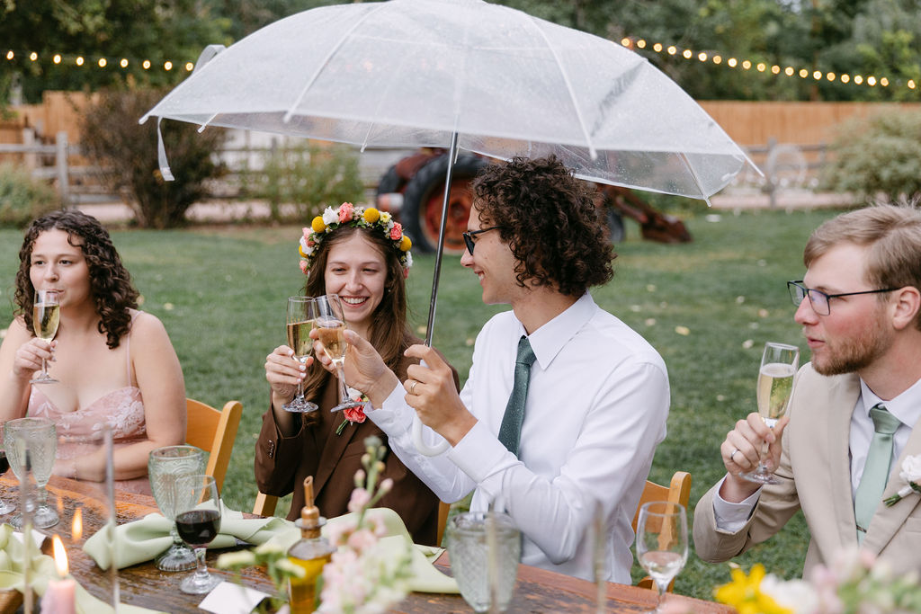 Candid wedding photography of bride and groom toasting their glasses at their outdoor wedding reception in Colorado